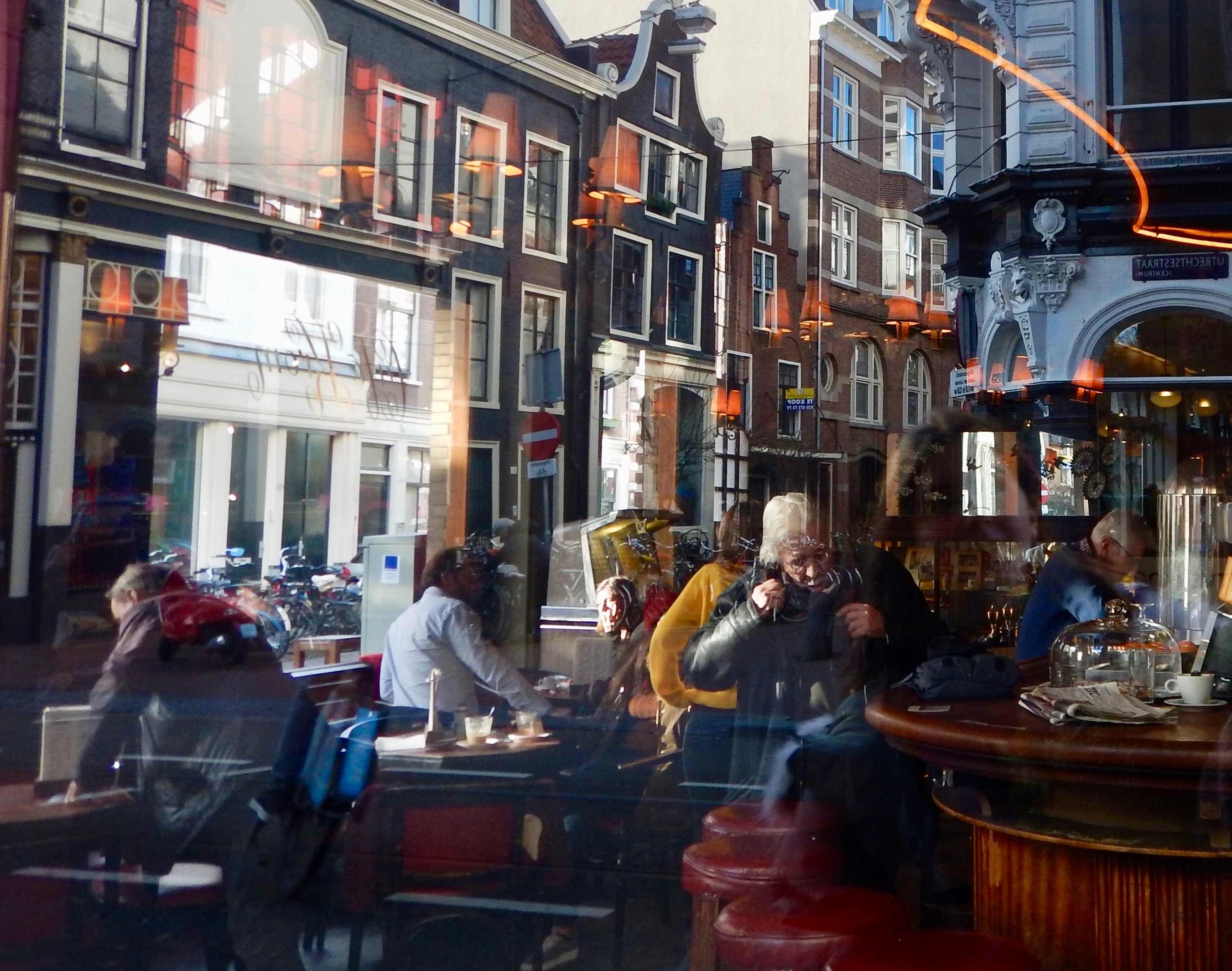 Passersby reflected on the glass window of a cafe in Amsterdam Central.